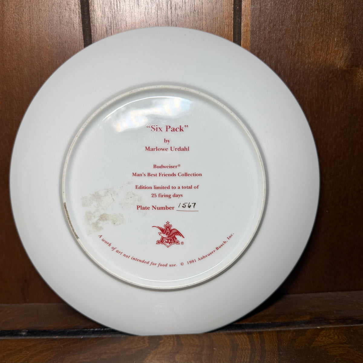 Vintage 1991 Budweiser collector plate featuring dalmatian puppies, designed by Marlowe Urdahl, displayed on a wooden surface.